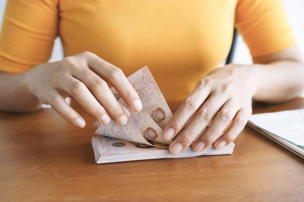 Hand of asian young women while sitting count money on their desk at home