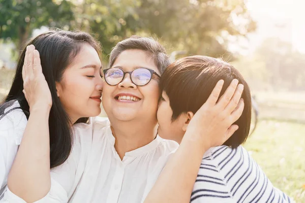 Азиатская мать и сын показывают любовь к бабушке поцелуем щеки в парке утром — стоковое фото