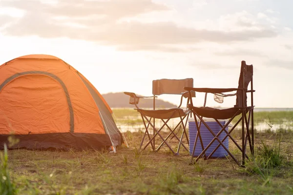 Camping tents, camp tent and chair by the river at sunset in the summer