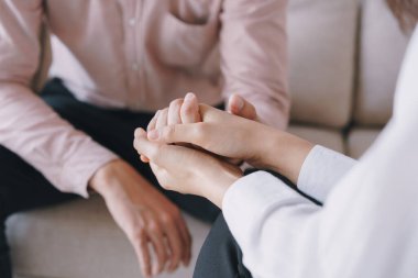 Psikiyatrist elleri hastasının avuç içini tutuyor. Psikolojik kadınlar kanepede otururken bir erkeğin elini tutup rahatlatıyorlar. Psikolog kavramı