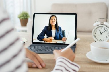 Omuz manzaralı. Asyalı kadın video konferansının liderleri tablette, iş kadını evden çalışıyor.