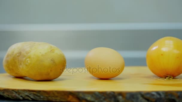 Batatas, cebola, ovo e farinha deitados em um suporte de madeira — Vídeo de Stock