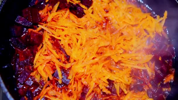 Morötter och rödbetor är simmered i en stekpanna — Stockvideo