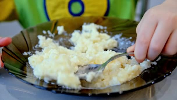 Мальчик ест кашу с тарелки — стоковое видео