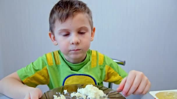 Мальчик ест кашу с тарелки — стоковое видео