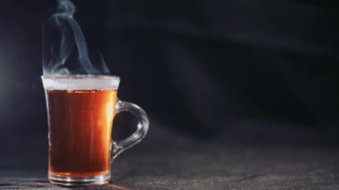 Karanlık bir arka plan şeffaf bardakta çay. Ağır çekim