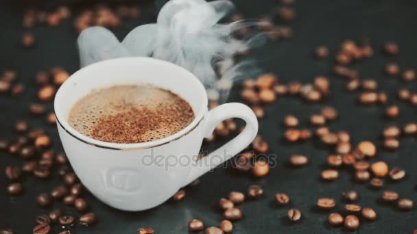 Taza con bebida caliente en granos de café tostados. Movimiento lento — Vídeos de Stock