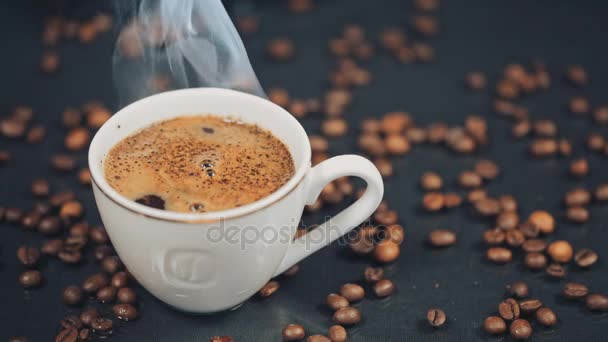 Taza con bebida caliente en granos de café tostados. Movimiento lento — Vídeos de Stock