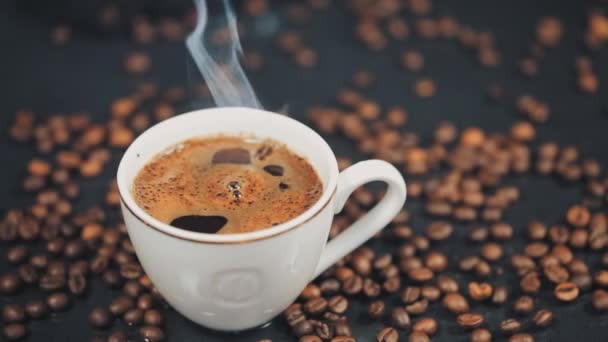 Xícara com bebida quente em grãos de café torrados. Movimento lento — Vídeo de Stock