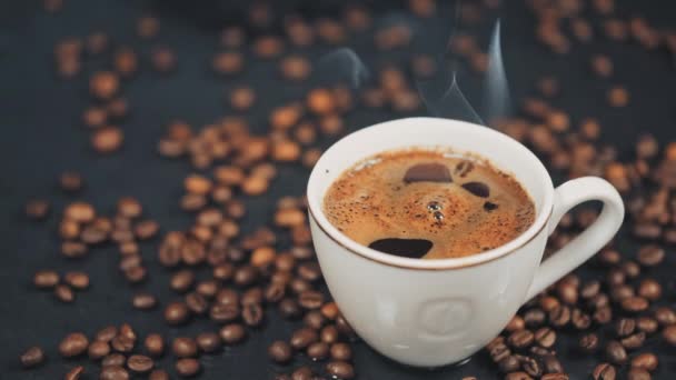 Xícara com bebida quente em grãos de café torrados. Movimento lento — Vídeo de Stock