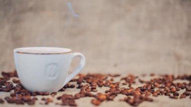 Kahve fincanı kahve çekirdekleri bir masada. Ağır çekim