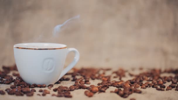 Tazza di caffè su un tavolo con chicchi di caffè. Rallentatore — Video Stock