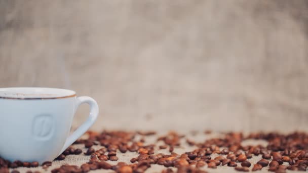 コーヒー豆とテーブルの上のコーヒー カップ。スローモーション — ストック動画