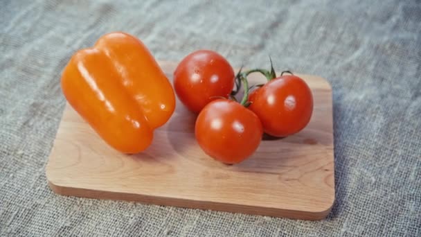 Tomatoes, bell pepper lying on a wooden Board — Stock Video