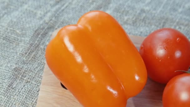 Tomatoes, bell pepper lying on a wooden Board. — Stock Video