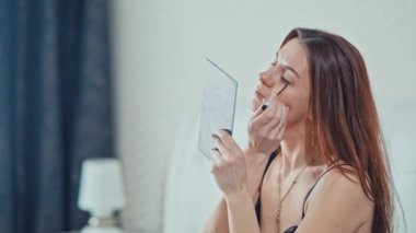 güzel kız makyaj yapıyor yatak odasında. Ağır çekim