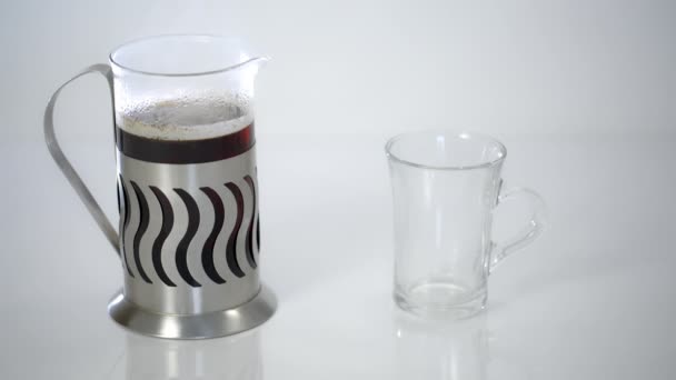 Théière transparente avec thé et une tasse transparente sur fond blanc — Video
