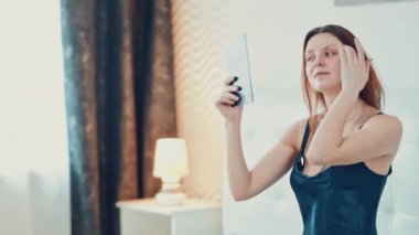 güzel kız makyaj yapıyor yatak odasında. Ağır çekim