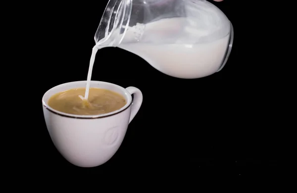Milch in eine Tasse Kaffee gegossen — Stockfoto