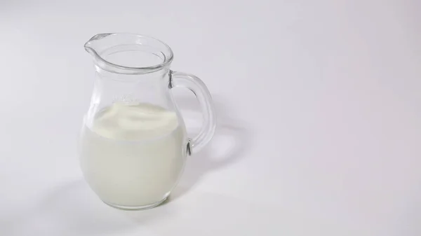Brocca di vetro con latte su sfondo bianco — Foto Stock