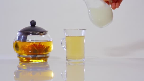 lait versé dans le thé dans une tasse transparente 