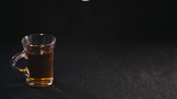 Leche vertiendo en el té en una taza transparente — Vídeo de stock