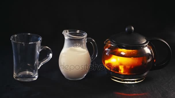 thé dans une théière en verre, le thé dans une tasse transparente et une petite cruche de lait 
