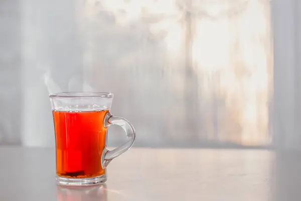 Чашка горячего чая на столе у окна — стоковое фото