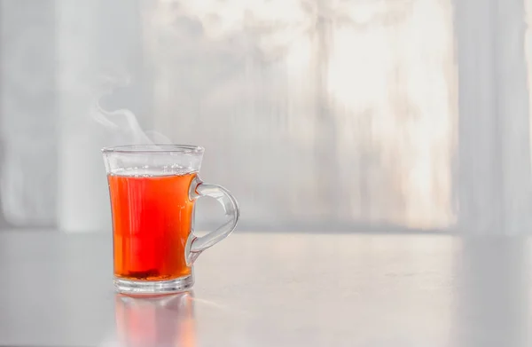 Прозрачный Кубок парящего горячего чая на столе против победы — стоковое фото