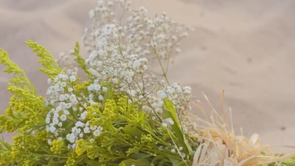 Een bouquet van veldbloemen op het zand — Stockvideo