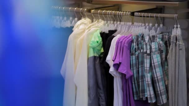 Магазин, одежда висит на вешалках — стоковое видео
