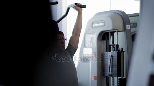 Hombre deportivo guapo está haciendo ejercicio en el centro de gimnasia — Vídeo de stock
