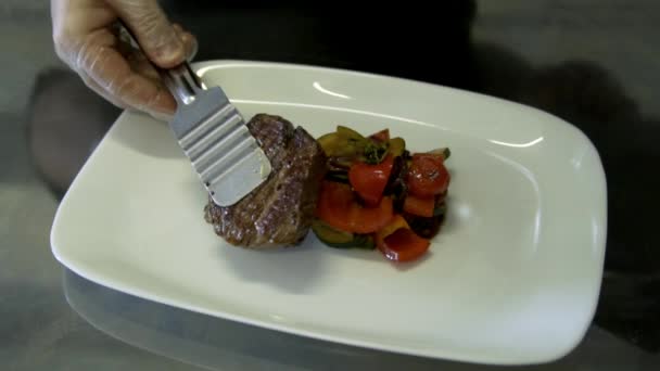 Шеф-повар кладет стейк на тарелку. замедленное движение — стоковое видео