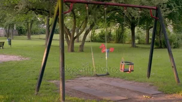 Um parque infantil vazio com baloiços — Vídeo de Stock