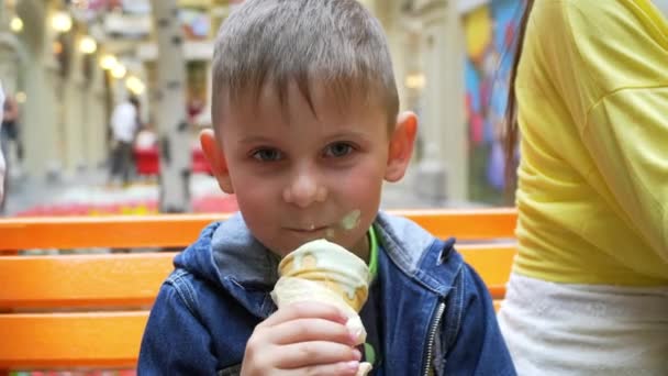 Chłopiec zjada lody na stole pomarańczowy. Guma — Wideo stockowe