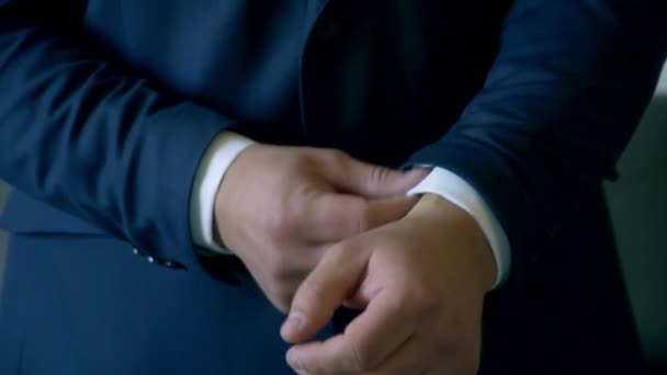 Мужчина выпрямляет манжеты на рубашке — стоковое видео