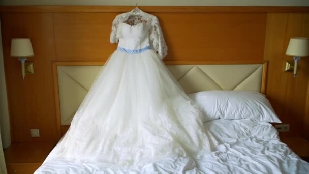 Элегантное свадебное платье лежит на кровати в номере отеля — стоковое видео