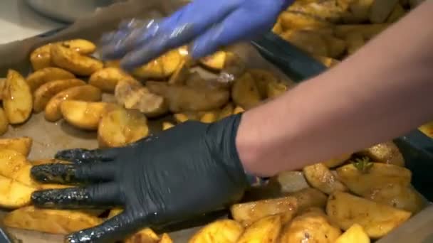 De kok zet de aardappelen op een bakplaat — Stockvideo