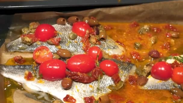 Pescado y poner los tomates en una bandeja para hornear — Vídeo de stock