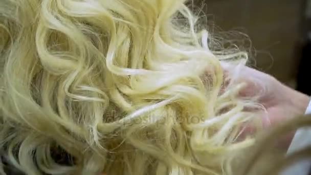 Cabeleireiro faz cabelo loiro de mulher jovem — Vídeo de Stock