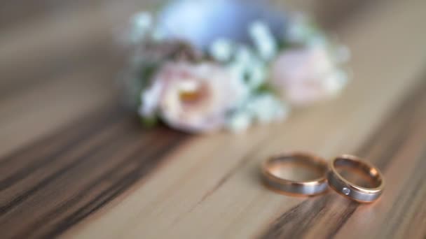 Boutonniere e anéis de casamento estão em uma placa de madeira — Vídeo de Stock