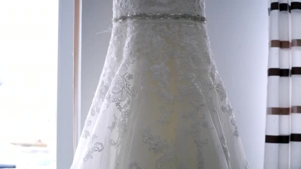 Свадебное платье висит на окне — стоковое видео