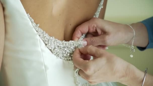 Brides beautiful back in fantastic white wedding dress and hands zipping it — Stock Video