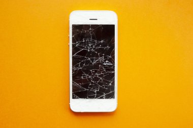 Turuncu arka planda kırılmış akıllı telefon ekranı.