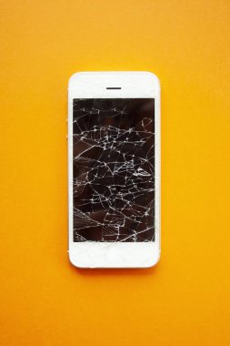 Turuncu arka planda kırılmış akıllı telefon ekranı.