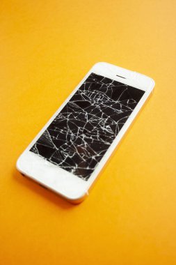 Turuncu arka planda kırılmış akıllı telefon ekranı.