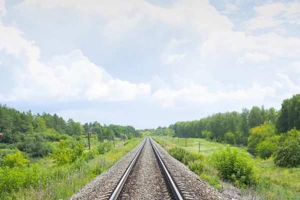 Un ferrocarril a través de los campos verdes de verano. Hermoso ferrocarril verde árbol paisaje cielo nubes. Hermoso paisaje. Transporte ferroviario . —  Fotos de Stock