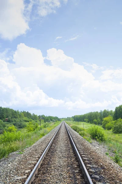 Un ferrocarril a través de los campos verdes de verano. Hermoso ferrocarril verde árbol paisaje cielo nubes. Hermoso paisaje. Transporte ferroviario . —  Fotos de Stock