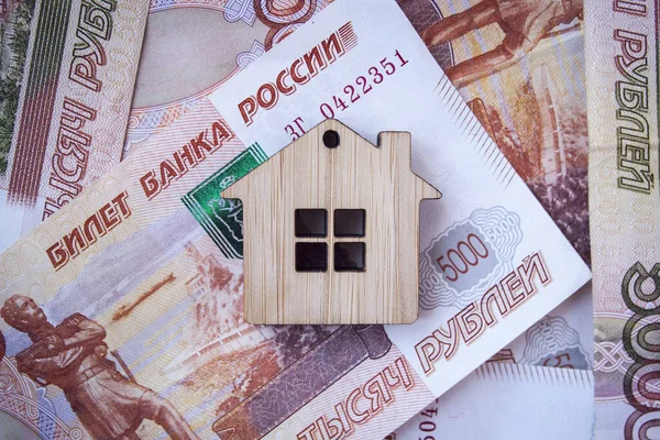 İpotek, sigorta, satın alma ve kira, emlak işi konsepti. Para üzerinde küçük ahşap ev oyuncağı. Arka planda rublem banknotlar.