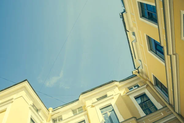 Saint-Petersburg in Russia courtyard with orange rough walls shot from bottom to the blue sky. Houses architexture and yards toned